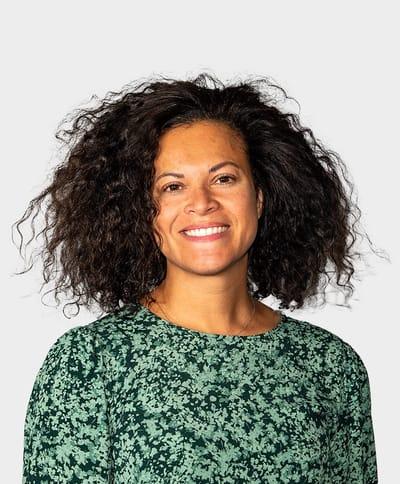 Lisa Martello head shot, a smiling female with brown curly hair wearing a white and black floral blouse