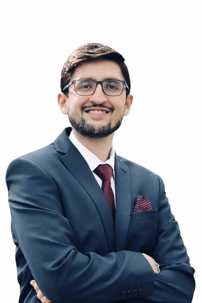 Rohit Malhotra head shot, a smiling male wearing glasses, short trimmed beard, wearing a suit, bergundy tie white shirt and dark blue blazar.